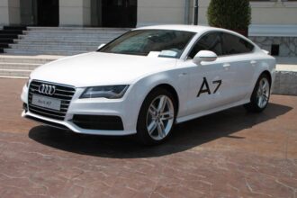 berline Audi sur une route avec paysage urbain en arrière-plan